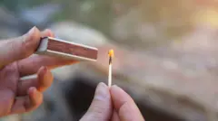 Людина тримає сірники в руках й розпалює вогонь на відкритому повітрі - стокове фото