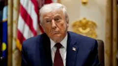 Donald Trump en costume bleu marine avec une cravate rouge.