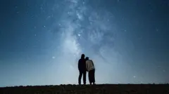 Un couple s'enlace en regardant les étoiles la nuit.