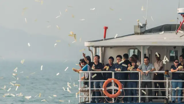 2012年10月4日,在香港南丫岛附近海域举行的渡轮碰撞事故罹难者悼念典礼上,哀悼者将纸钱抛入海中。