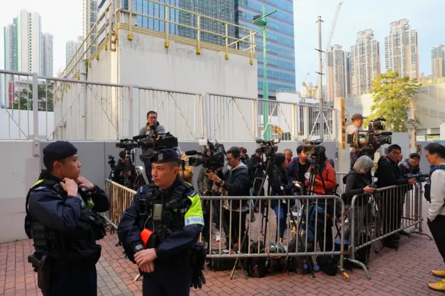 在香港,媒体记者在西九龙裁判法院大楼外的警戒线内等候,等待报道黎智英案件。