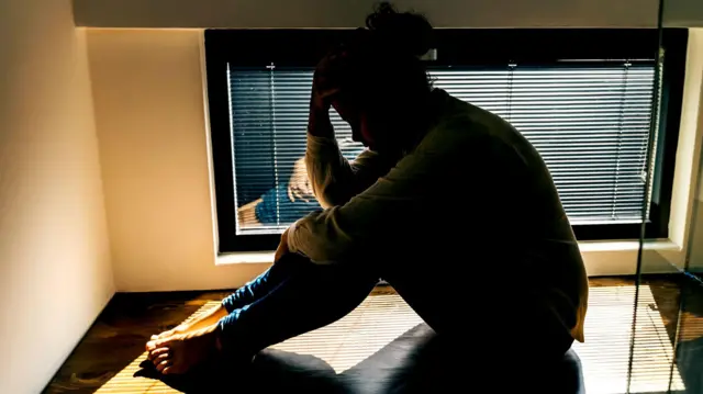 ያዘነች ሴት መስኮት አጠገብ ቁጭ ብላ