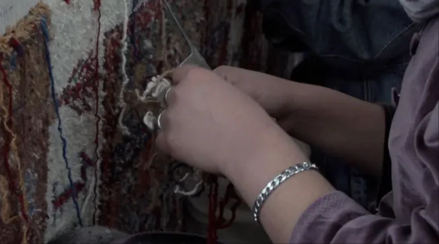 یک زن افغان در حال فرش بافی فقط دستانش دیده میشود