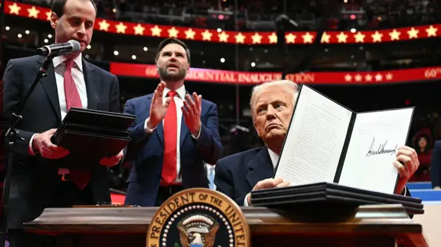 美国总统特朗普(右)手持行政命令,宣布美国退出《巴黎协定》(20/1/2025)