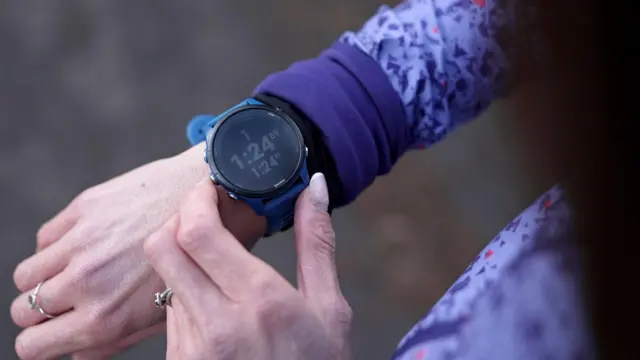 一名女性正在检查她的智能手表,按下按钮并查看萤幕上显示的统计数据