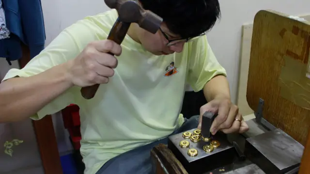 一名男子正在打制金粒。