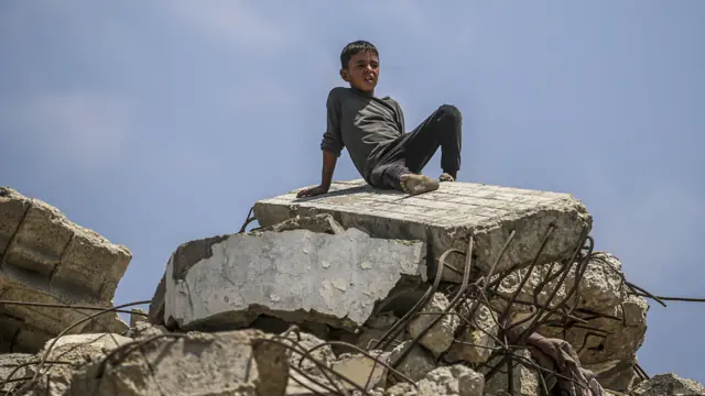 ፍልስጤማዊ ታዳጊ በፈራረሰ ቤት ላይ ተቀምጦ