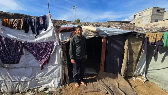 نازح فلسطيني في مكب نفايات اليرموك يقف أمام خيمته بعد أن فشلت السدود التي أقامها في منع المياه