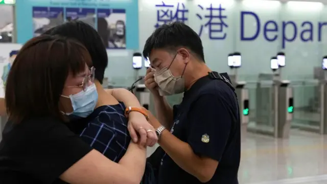 在香港机场的离港闸前,两人相拥,另外一人以纸巾抹眼泪。