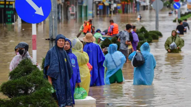 أشخاص يحملون أمتعتهم يخوضون مياه الفيضانات في نها ترانج، مقاطعة خانه هوا، فيتنام