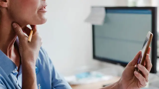 በያዘችው ስልክ በቪዲዮ እያወራች አንገቷን የምትመለከት ሴት ምስል