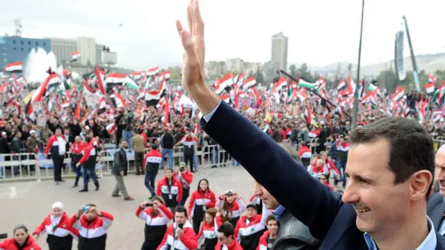 الرئيس السوري المعزول بشار الأسد يلوح لأنصاره خلال ظهور علني نادر له في دمشق في 11 يناير/كانون الثاني 2012.