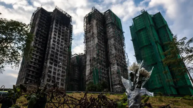 Flowers are seen in front of the Wang Fuk Court apartment blocks in the aftermath of the deadly November 26 fire in Hong Kong's Tai Po district on December 3, 2025.