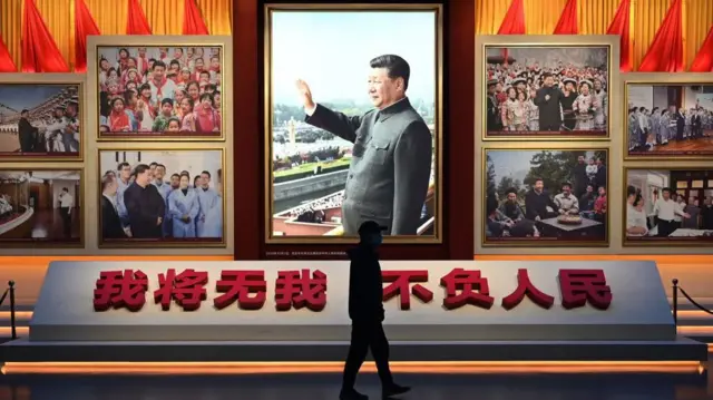 一位男子走过挂满习近平肖像的展览臺前