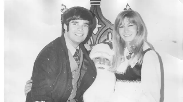 一张黑白照片中,卡罗尔先生与韦伯女士坐在圣诞老人的腿上,对着镜头微笑。