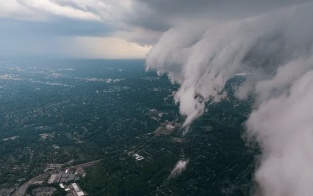 تصویریی از درون هواپیما از فراز یک شهر، بخشی از ابرها هم در تصور دیده میشوند