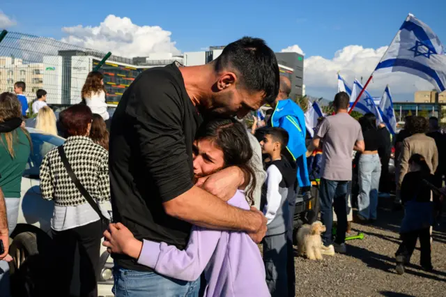 A father comforts his daughter after the first helicopter arrived carrying hostages to Bellinson Hospital in Israel