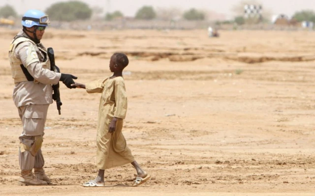 یک کودک با یک سرباز دست میدهد