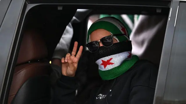 سيدة تشير بعلامة النصر خلال احتفالات في دمشق بمناسبة الذكرى الأولى لسقوط الأسد (8 ديسمبر/ كانون الأول 2025)