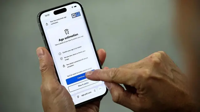 一名男子手持手机,展示如何进行 Yoti 公司提供的年龄估测检测