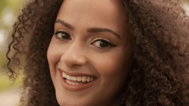 ፀጉሯ ፍሪዝ የሆነ የምትስቅ ሴት