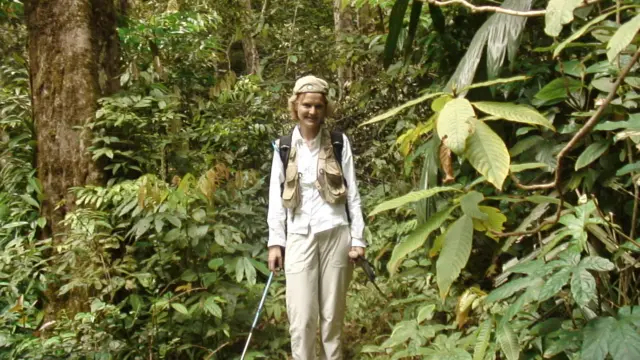 آنت در میان پوشش گیاهی سرسبز، با یک کوله پشتی و یک عصای کوهنوردی