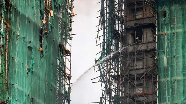 2025年11月27日,香港大埔区宏福苑,一名消防员正用水枪扑灭仍在燃烧的住宅大楼。