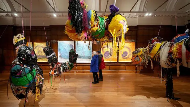 چند اثر هنری در یک گالری هستند و دو نفر آنها را تماشا میکنند