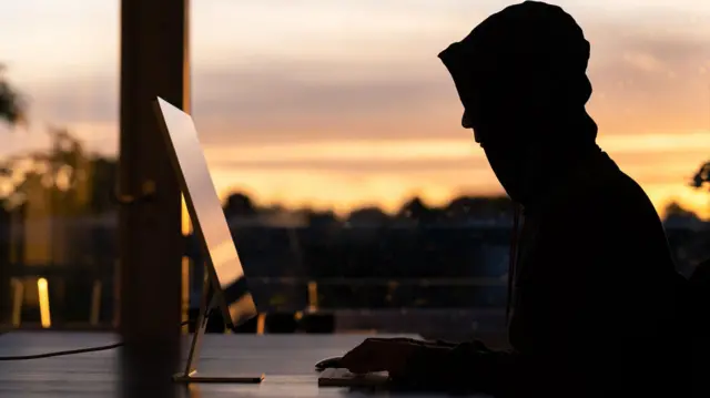 ኮምፒውተሩ ፊት ለፊት ራሱን ሸፋፍኖ የተቀመጠ ወንድ