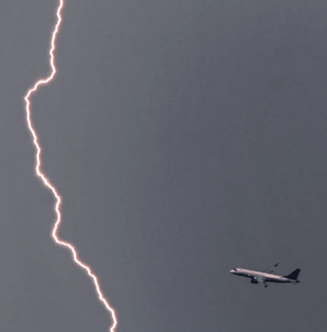 هواپیمای در آسمان نزدیک یک صاعقه بزرگ