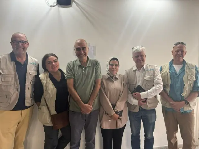 عکسی که در دفتر مرکزی شبکه سازمانهای مردمنهاد فلسطینی در شهر غزه، به همراه عدهای از مقامهای یونیسف در جریان جنگ غزه گرفته شده است. شوا با تیشرت سبز در مرکز عکس دیده میشود