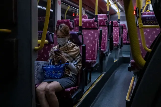 2022年11月,一名女子坐在巴士里面,正看着手机。