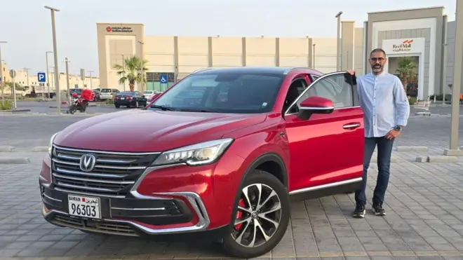 ቻይና ሠራሽ መኪናውን ይዞ የቆመ ሰው