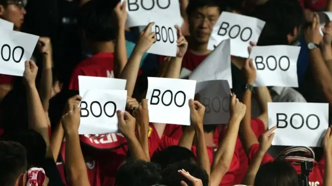 有一些观众则举起印有“Boo”字样的纸片,并在奏国歌时背向球场。