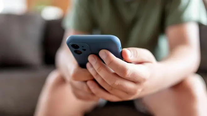 A young boy's hands holding a smartphone