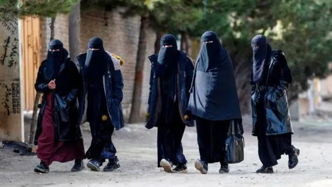 تصویر پنج زنی که حجابهای سیاه بر تن دارند. این زنان نقاب سیاه نیز پوشیده اند و در جادهای در کنارهم قدم میزنند.