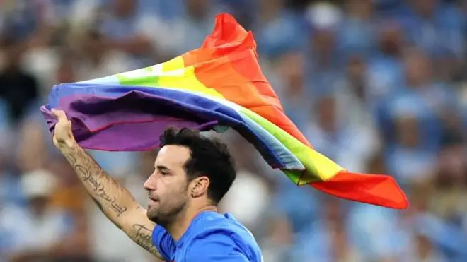 تماشاگری که در جام جهانی قطر حین بازی اروگوئه با پرتغال با پرچم رنگین کمان به زمین مسابقه دوید