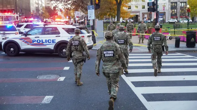 أفراد من الحرس الوطني يسيرون بالقرب من منطقة مطوقة بعد إطلاق النار على اثنين من أفراد الحرس الوطني بالقرب من البيت الأبيض في واشنطن العاصمة، الولايات المتحدة.