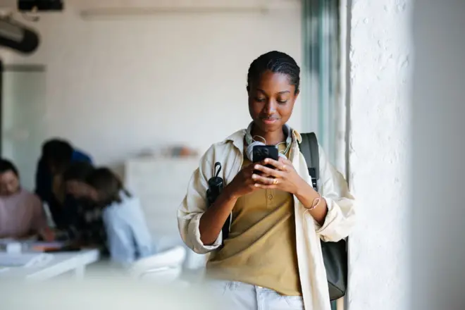 ስልኳን የምትመለከት ተማሪ