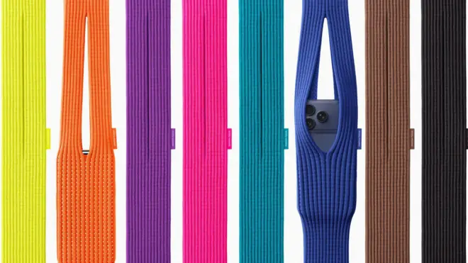 展示了八个色彩鲜豔的针织iPhone Pocket包,其中两个放有iPhone,从左至右的颜色依序为:黄色、橙色、紫色、粉红色、绿松色、蓝色、棕色与黑色。