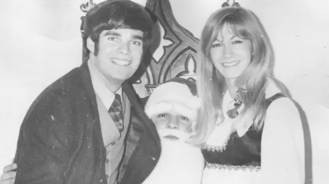 Mr Carroll and Ms Webber in a black-and-white photo, sitting on the lap of a Santa Claus and smiling at the camera