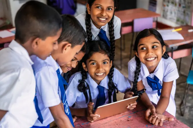 ශ්රී ලංකාවේ සීගිරිය ප්රදේශයේ පන්ති කාමරයක ඩිජිටල් ටැබ්ලටයක භාවිත කරන ශ්රී ලාංකික පාසල් දරුවන් කිහිප දෙනෙක්.