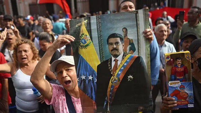 在委内瑞拉,一些戴着帽子、穿着色彩鲜豔衣服的老年抗议者手持委内瑞拉总统的照片和一个大型玩偶,此前这名总统被美军捉拿出境。