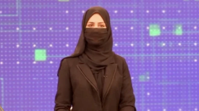 خبرنگارزن تلویزیون خصوصی طلوع در حال اجرای برنامه با ماسک صورت