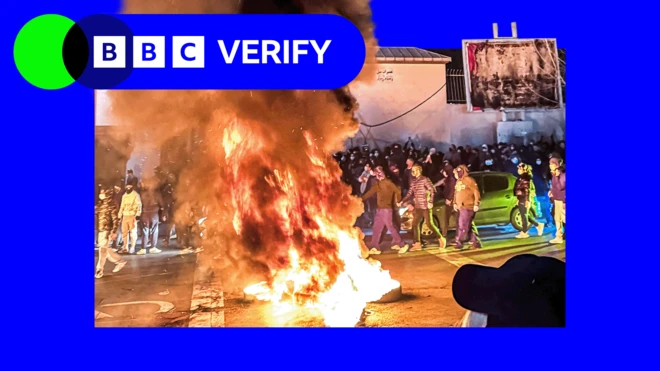 BBC事实核查品牌图框:德黑兰示威期间一处地点,马路中心一堆杂物起火,火焰与浓烟飙喷