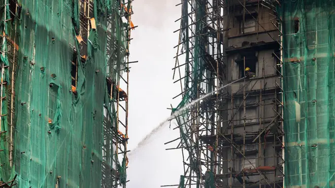 2025年11月27日,香港大埔区宏福苑,一名消防员正用水枪扑灭仍在燃烧的住宅大楼。