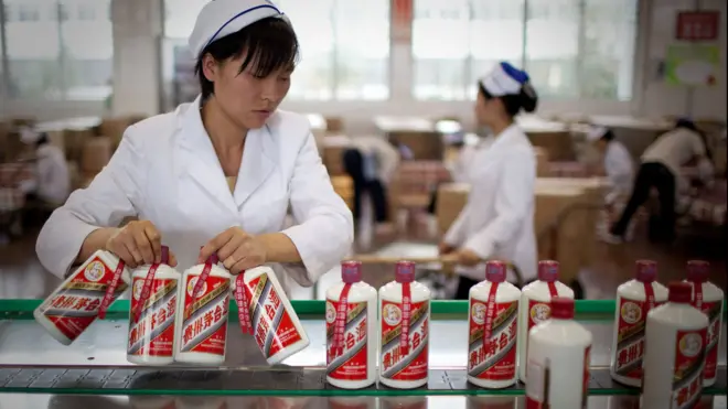 Employee pick bottles of Moutai baijiu on the production line at the Kweichow Moutai Co. factory