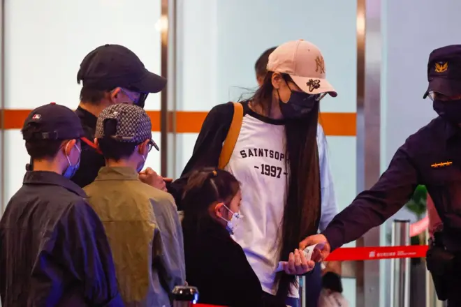 Chinese influencer 'YAYA' (Liu Zhenya) with a white hat enters the departure hall, as she complies with Taiwan's legal order to leave Taiwan after her residency was revoked for posting videos advocating 'One China' and 'Unification with China by force', at Songshan Airport in Taipei, Taiwan, on March 25, 2025.