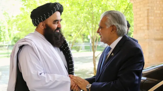 امیر خان متقی و اسحاق دار باهم دست داده و لبخند دارند.