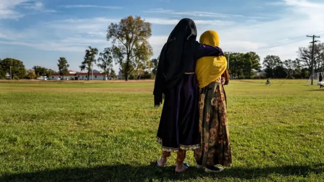 Afghan refugee girls watch a soccer match near where they are staying in the Village at the Ft. McCoy US Army base in 2021